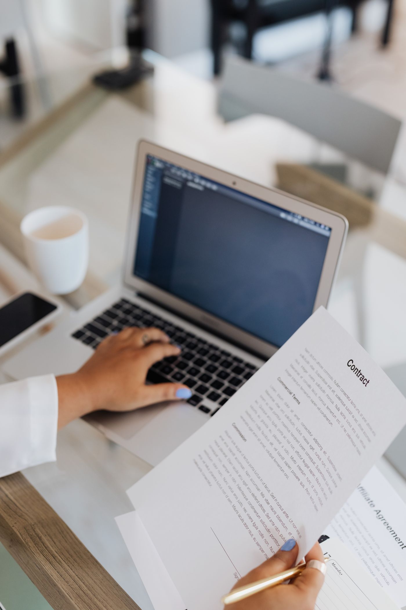 Persona revisando documentos junto a una computadora portátil
